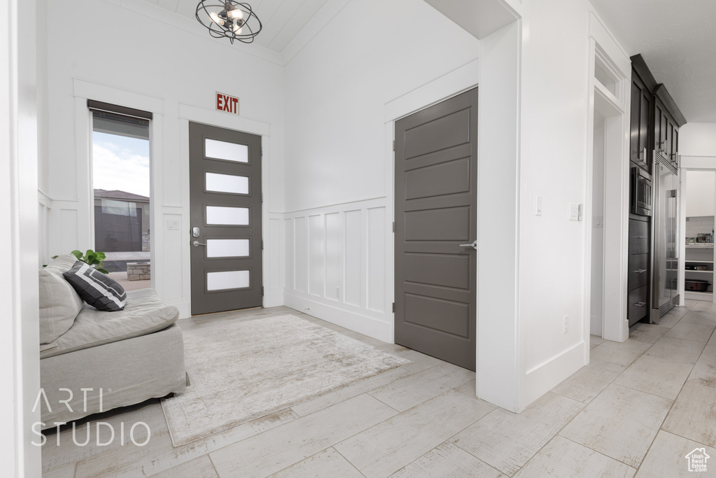 Foyer entrance with an inviting chandelier, wainscoting, and a decorative wall