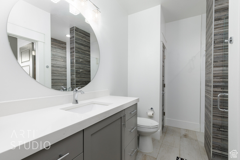 Full bathroom featuring toilet, baseboards, a shower stall, and vanity