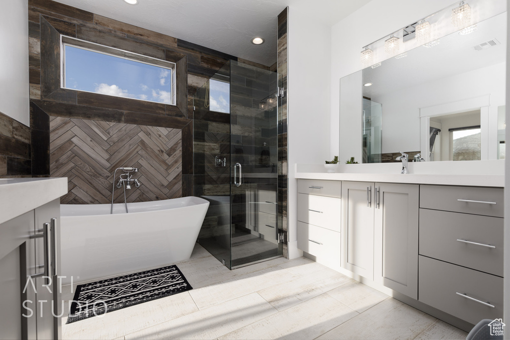 Full bath with vanity, recessed lighting, a freestanding bath, a shower stall, and a wealth of natural light