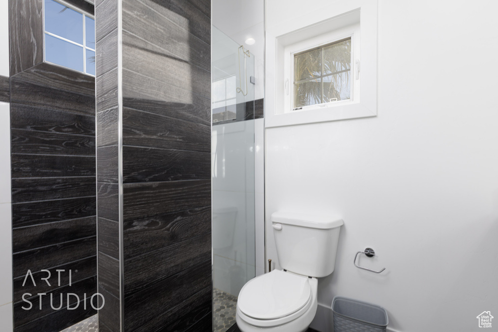 Full bath with a healthy amount of sunlight, walk in shower, and toilet