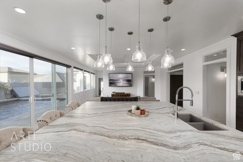 Kitchen featuring recessed lighting, a sink, pendant lighting, and light stone countertops