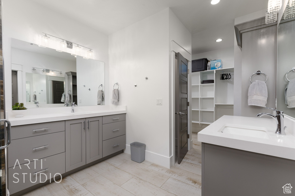 Full bath with vanity, baseboards, recessed lighting, and a walk in closet