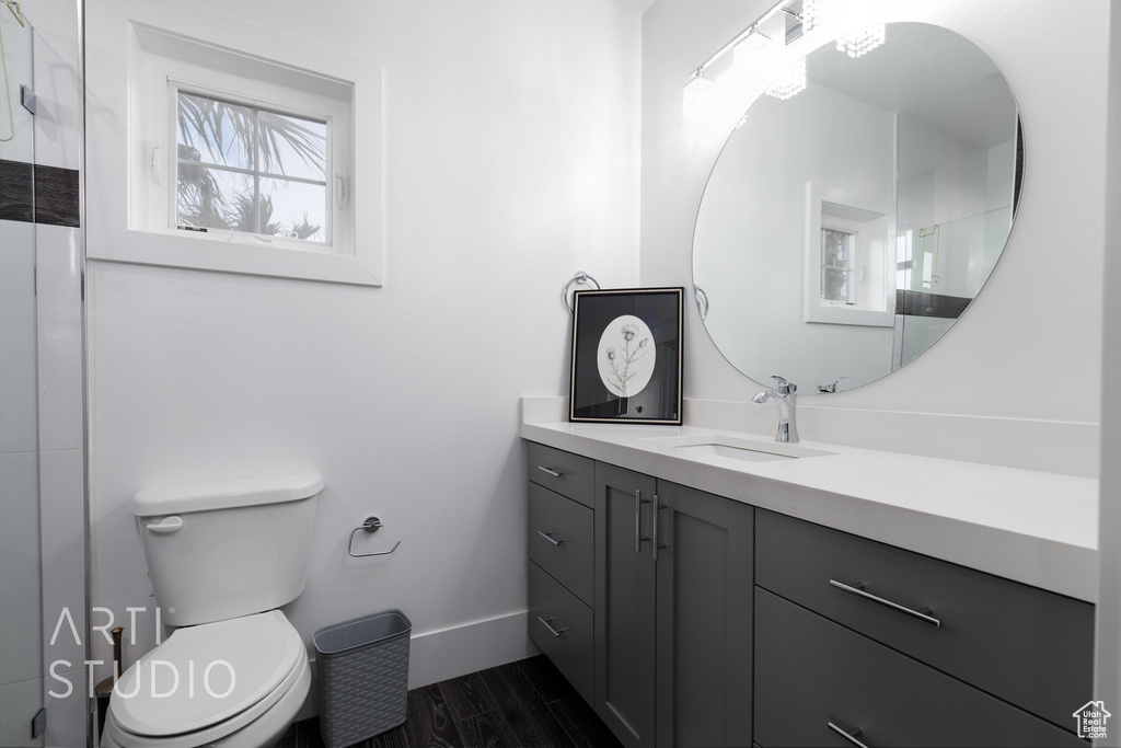 Full bath with vanity, wood finished floors, a shower, toilet, and baseboards