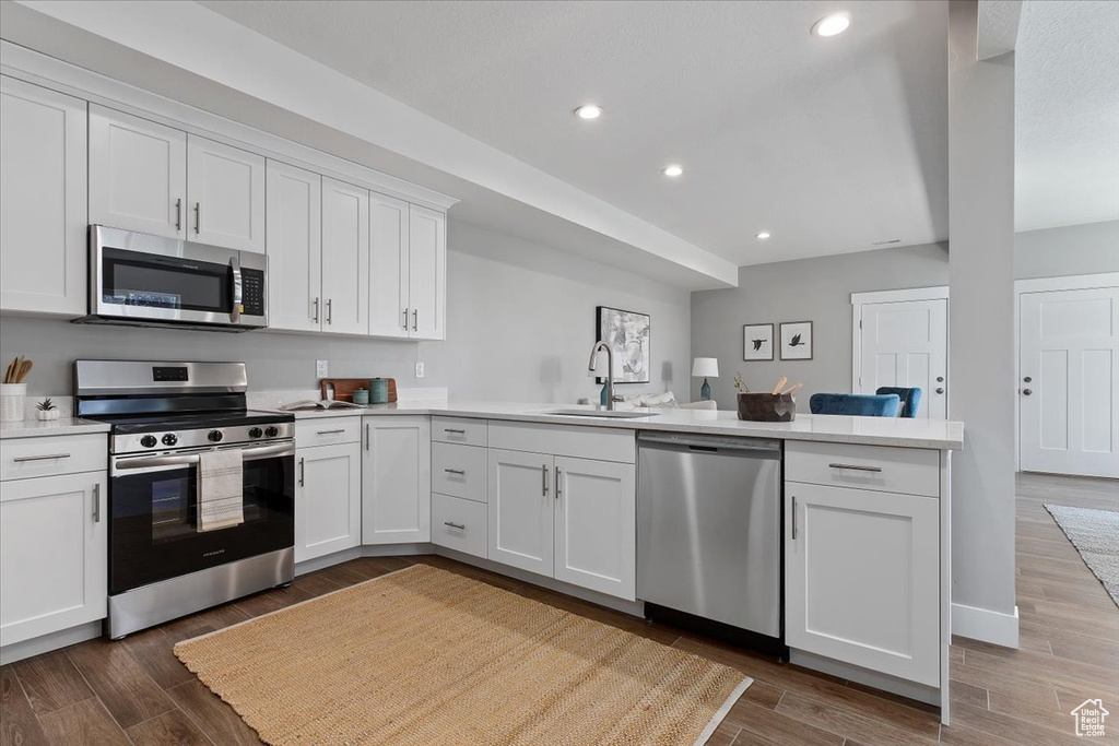 Kitchen featuring a sink, appliances with stainless steel finishes, a peninsula, and light countertops