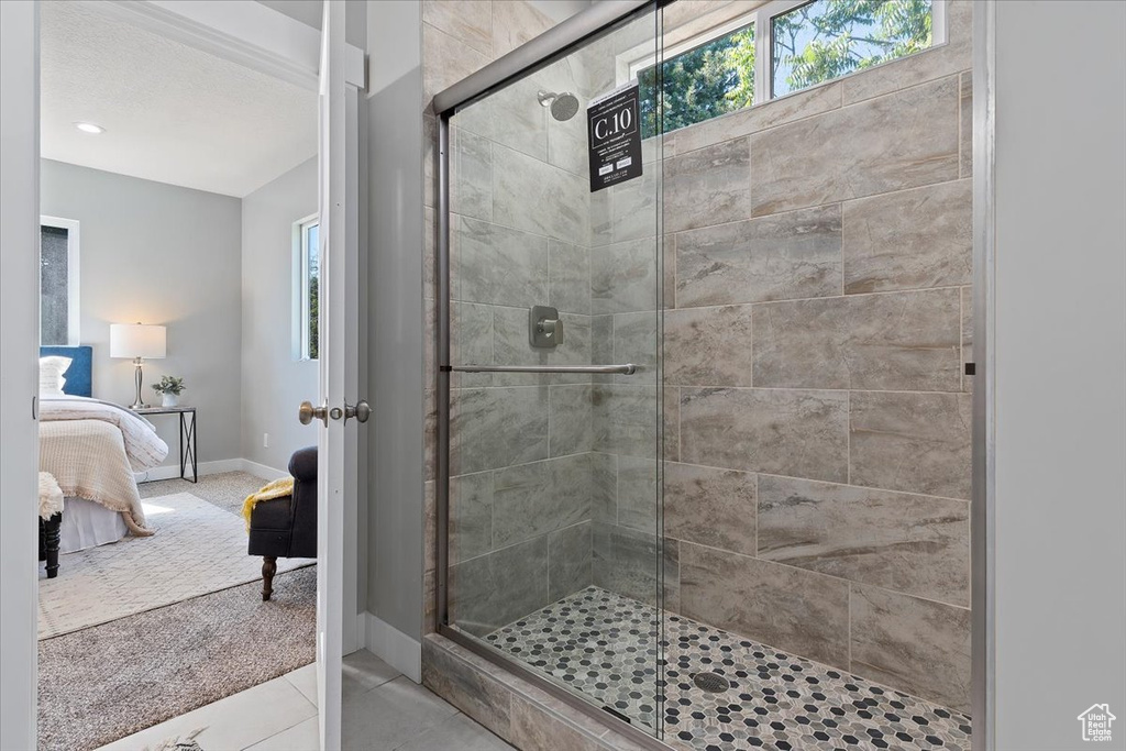 Ensuite bathroom with ensuite bathroom, baseboards, tile patterned floors, and a shower stall