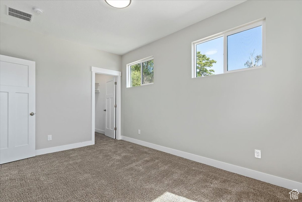 Unfurnished bedroom with visible vents, a closet, baseboards, a walk in closet, and carpet