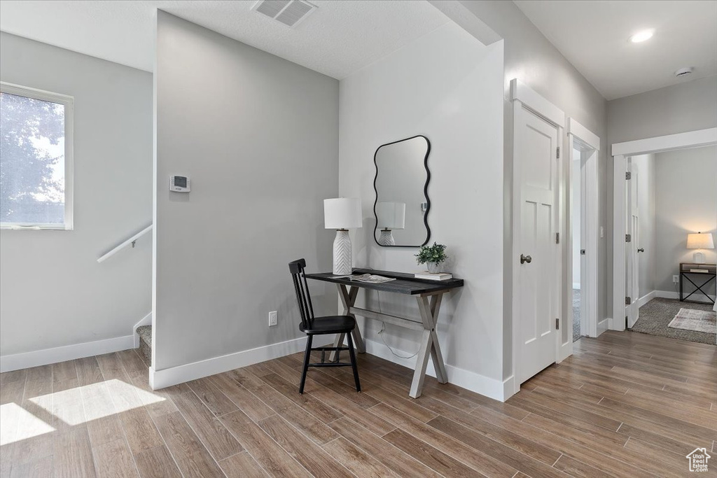 Hallway with baseboards, visible vents, and wood finished floors