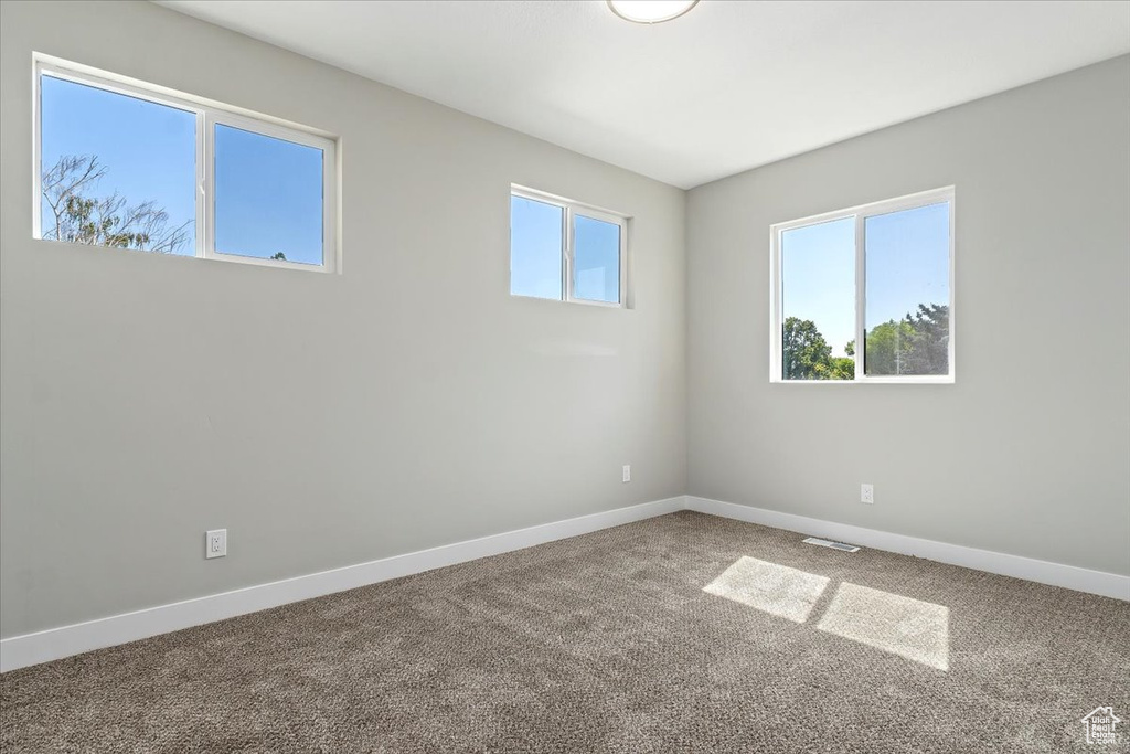 Empty room featuring baseboards, carpet flooring, and visible vents