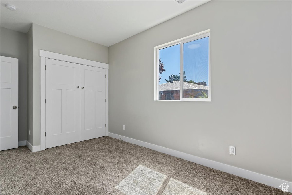 Unfurnished bedroom with carpet floors, baseboards, and a closet