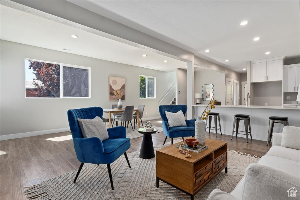Living room featuring recessed lighting, baseboards, stairs, and light wood-style flooring