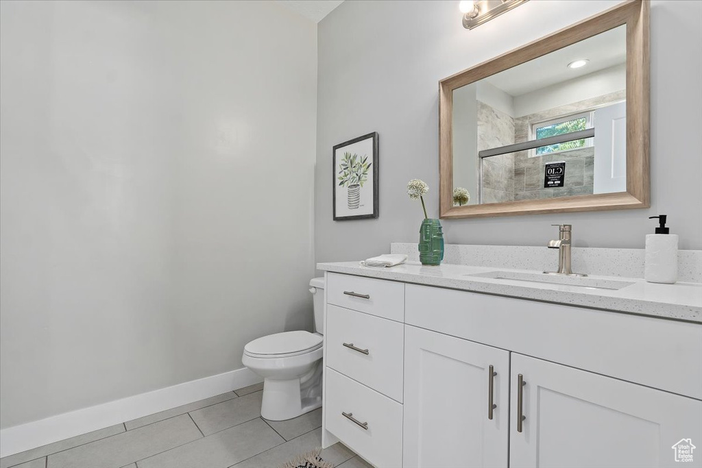 Full bathroom featuring tile patterned flooring, a stall shower, vanity, baseboards, and toilet