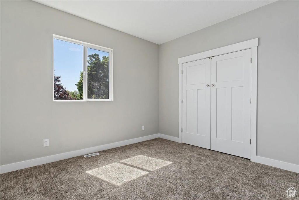 Unfurnished bedroom featuring visible vents, carpet, baseboards, and a closet