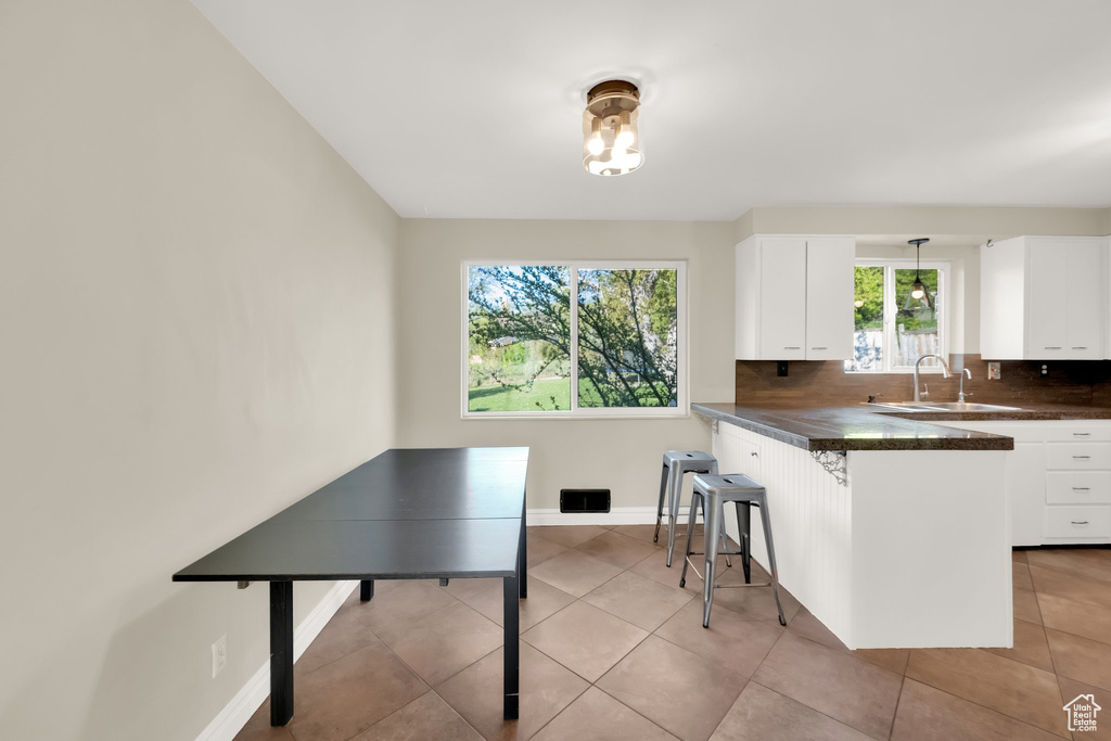 Kitchen with white cabinetry, a breakfast bar area, and dark countertops