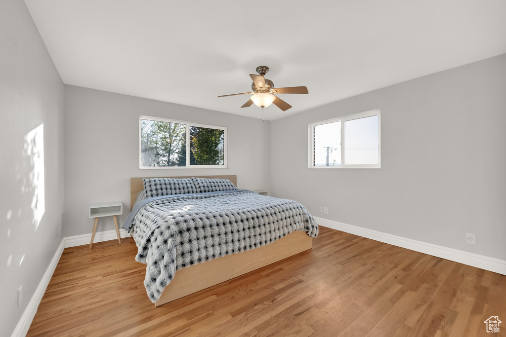 Bedroom featuring baseboards, multiple windows, and wood finished floors