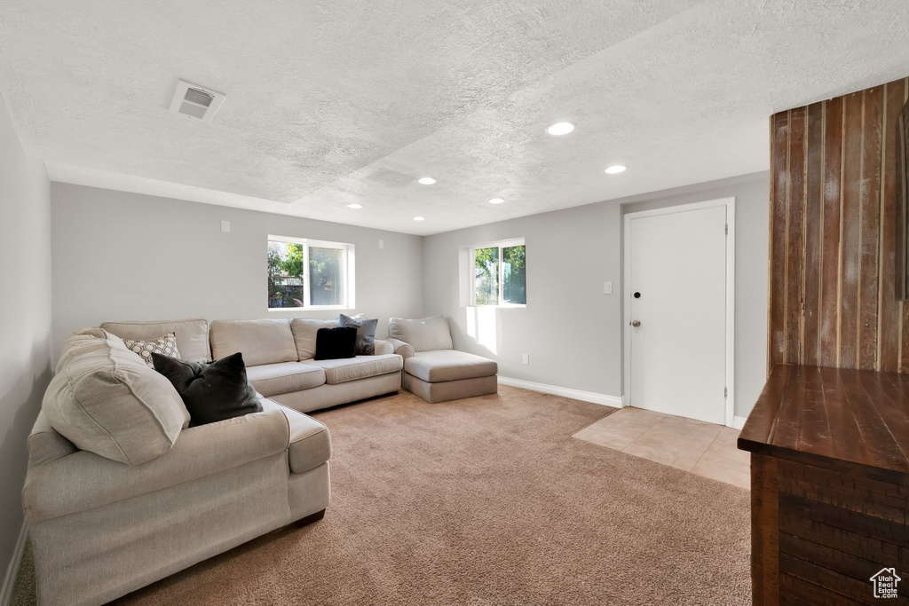 Living room featuring visible vents, recessed lighting, a textured ceiling, and light carpet