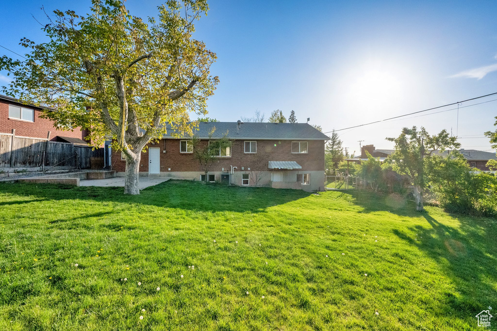 Rear view of property with brick siding, a fenced backyard, and a yard
