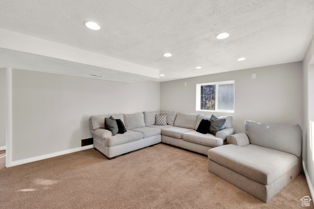 Carpeted living room with recessed lighting, a textured ceiling, and baseboards