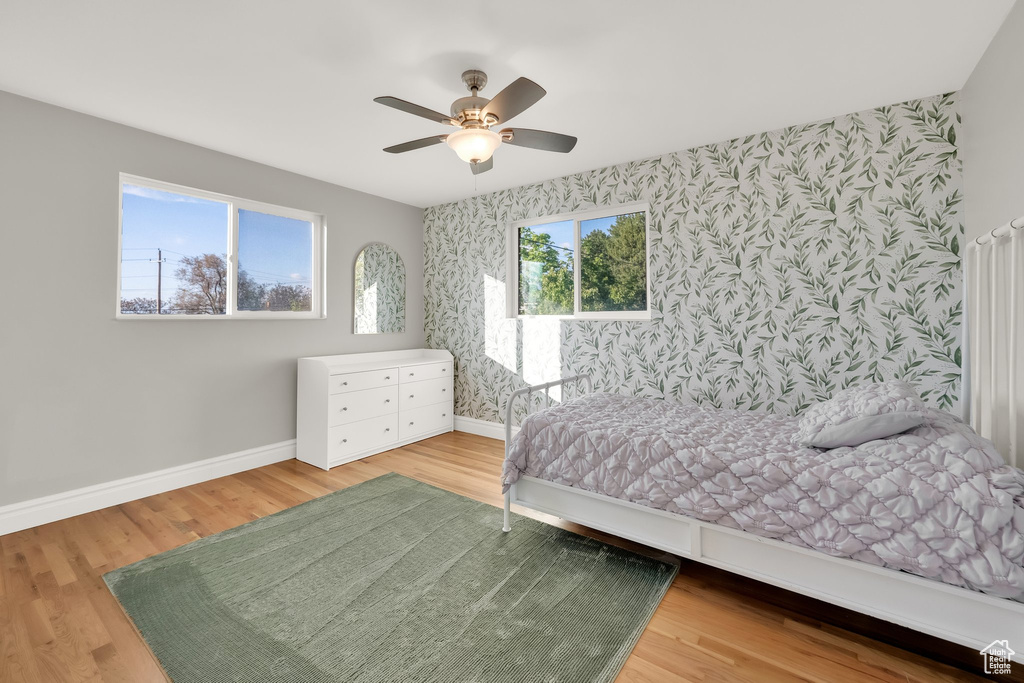 Bedroom with baseboards, an accent wall, and wallpapered walls