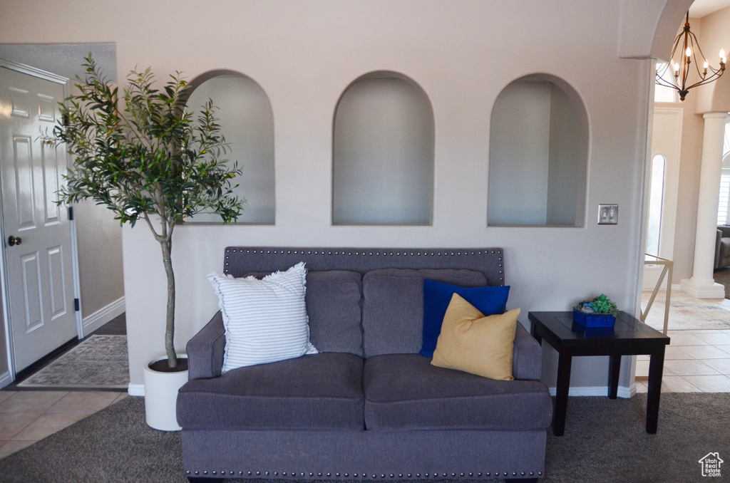 Tiled living area featuring carpet floors, baseboards, and an inviting chandelier
