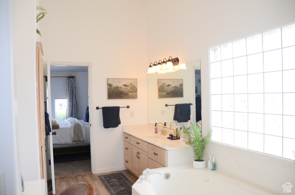 Full bathroom featuring a healthy amount of sunlight, vanity, wood finished floors, and connected bathroom