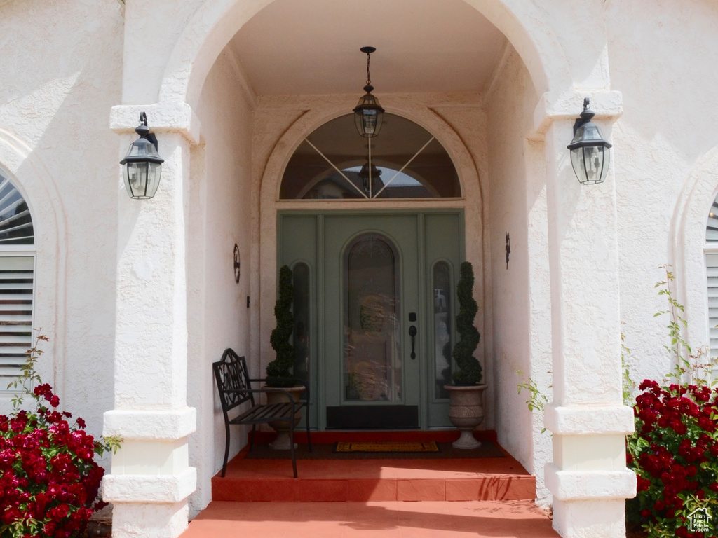 View of exterior entry featuring covered porch and stucco siding