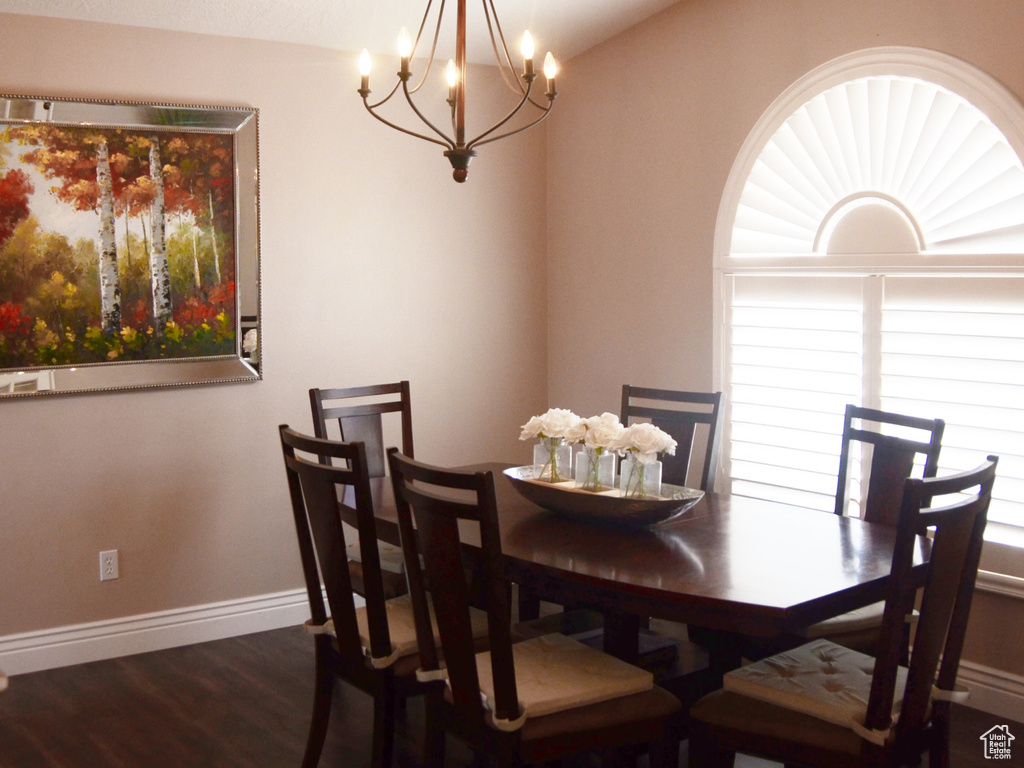 Dining area with baseboards, vaulted ceiling, dark wood-type flooring, and a notable chandelier