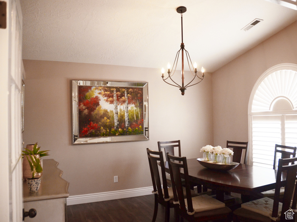 Dining area with visible vents, dark wood-style flooring, baseboards, a chandelier, and vaulted ceiling