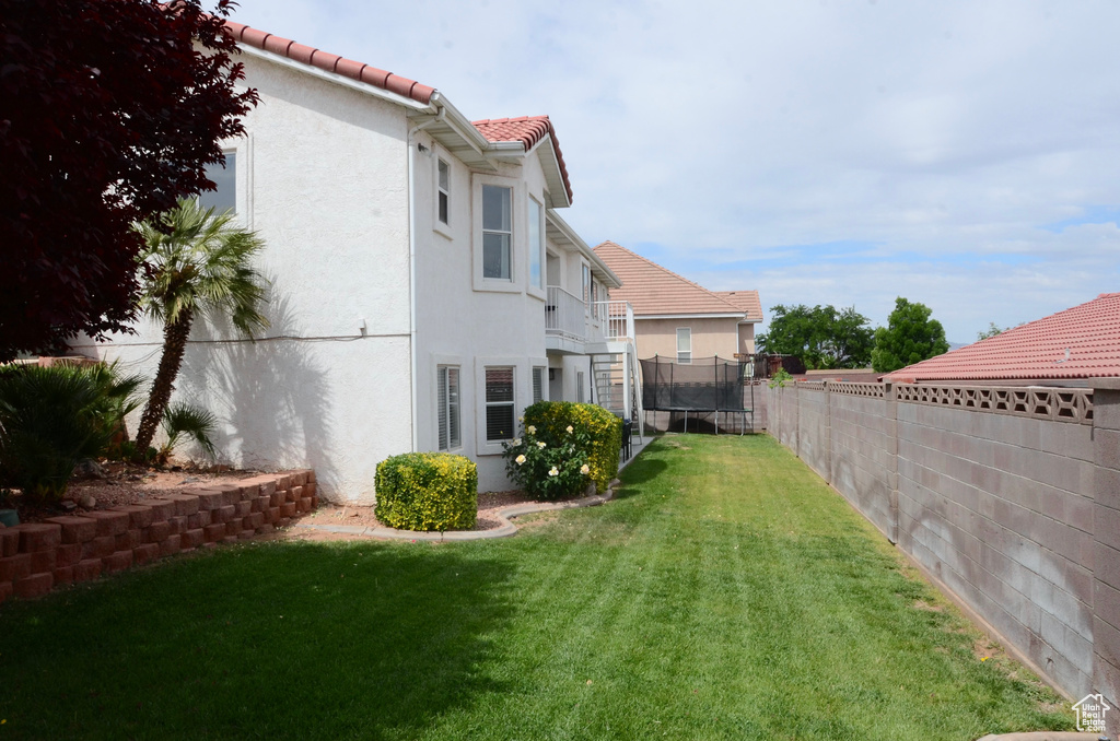 View of yard with a fenced backyard, a trampoline, and a balcony