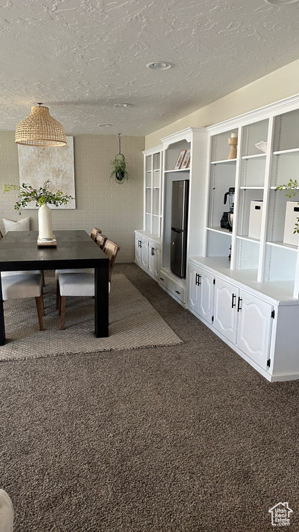 Interior space featuring dark colored carpet and a textured ceiling