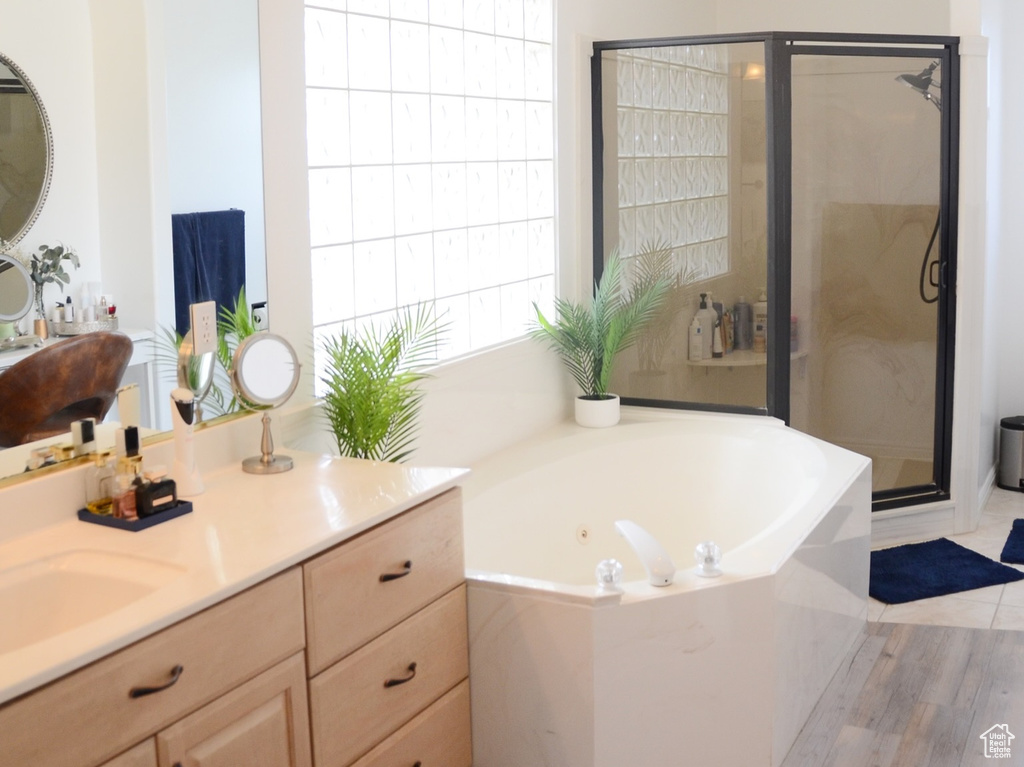 Bathroom with a garden tub, a shower stall, vaulted ceiling, wood finished floors, and vanity