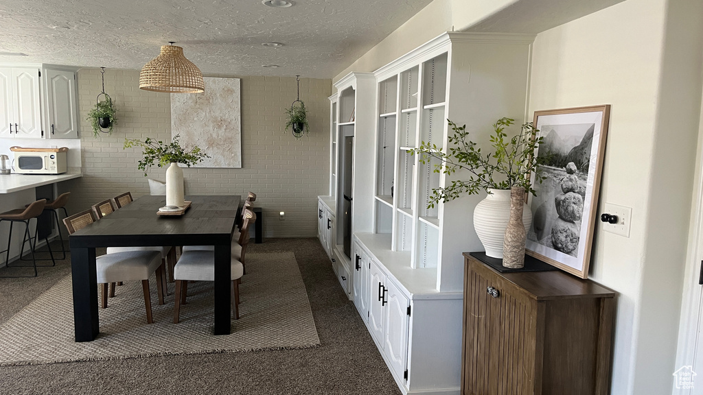 Dining space featuring dark carpet and a textured ceiling