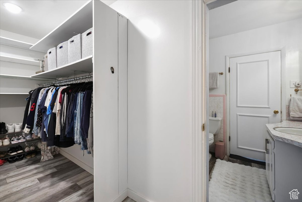 Walk in closet with wood finished floors and a sink