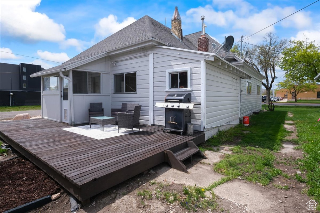 Rear view of property with a deck, a chimney, and roof with shingles