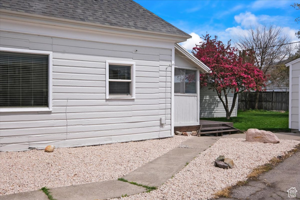 View of side of home featuring fence and roof with shingles