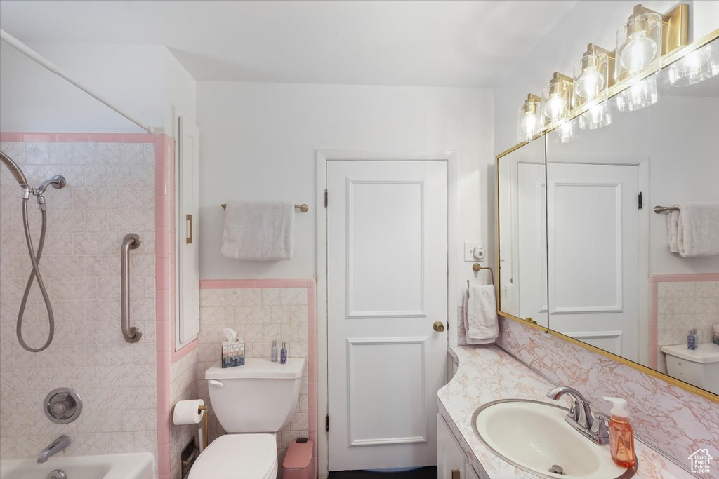 Full bath with wainscoting, tile walls, toilet, shower / tub combination, and vanity