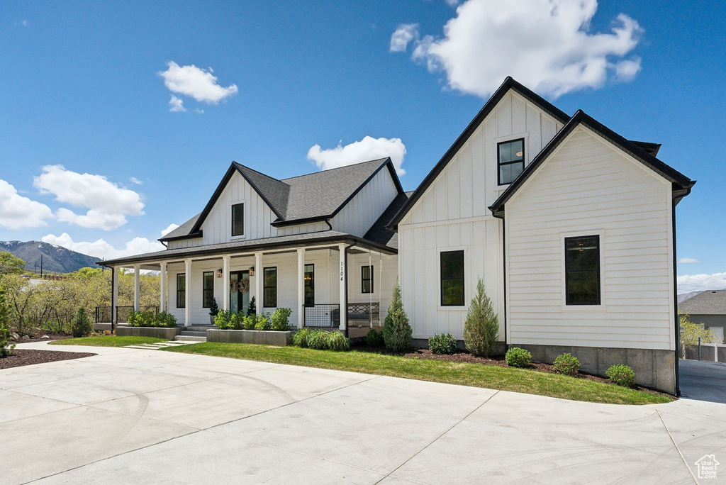 Modern inspired farmhouse featuring board and batten siding, a mountain view, and a porch