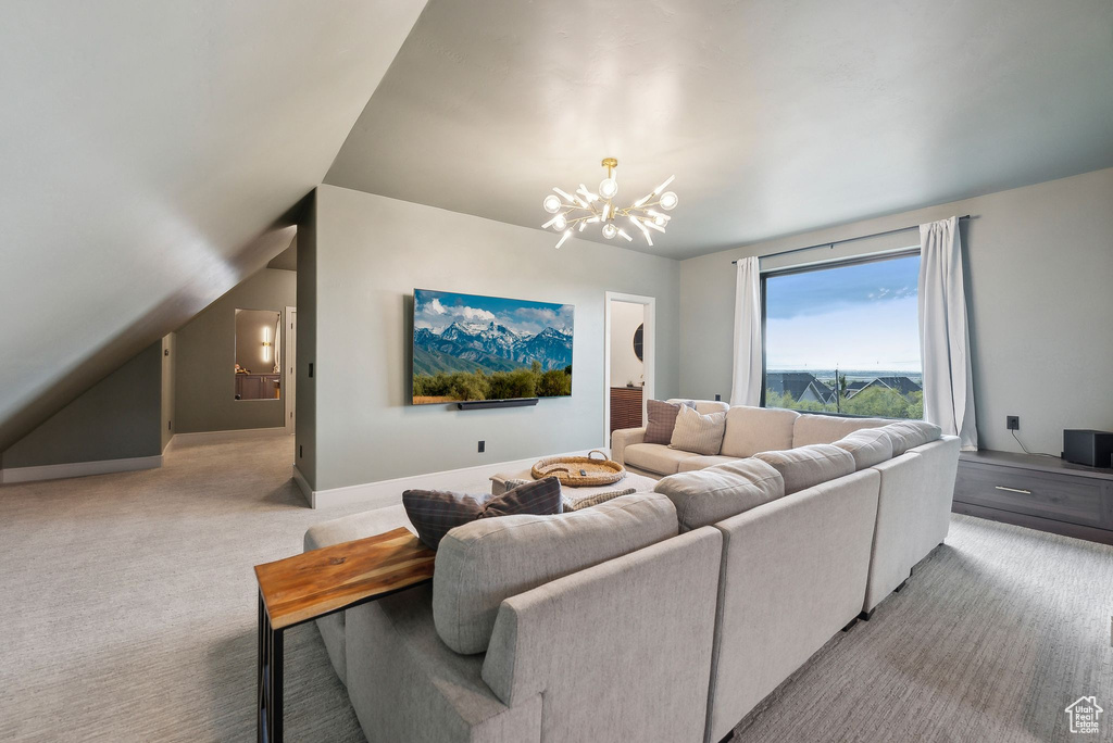 Carpeted living area featuring baseboards, a chandelier, and vaulted ceiling