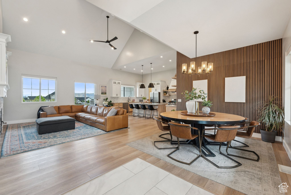 Dining space with recessed lighting, high vaulted ceiling, baseboards, and light wood finished floors