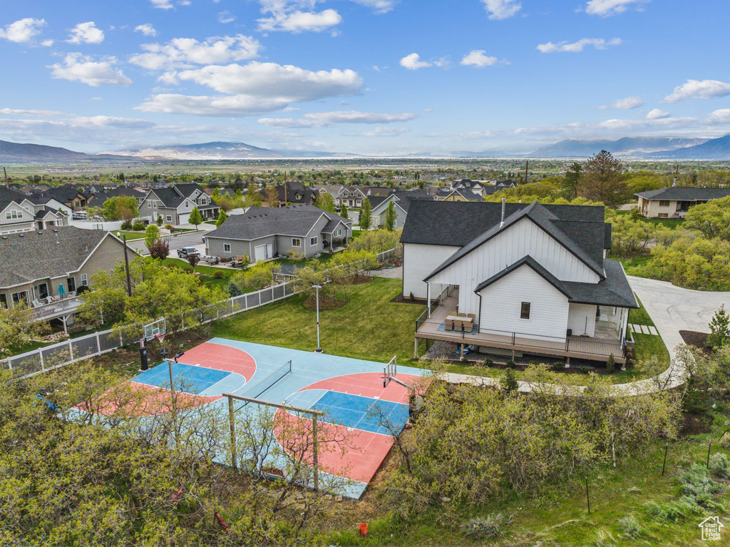 View of basketball court featuring a residential view, fence, basketball hoop, and a mountain view