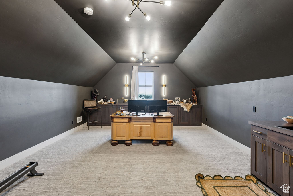 Home office with light colored carpet, baseboards, and vaulted ceiling
