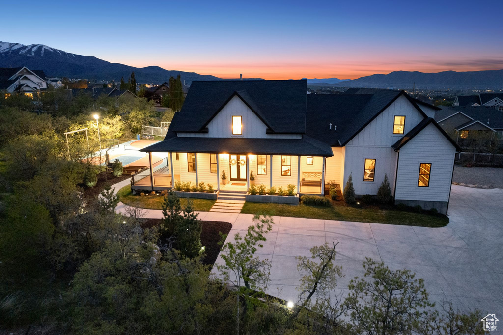 Back of house with concrete driveway, covered porch, board and batten siding, and a mountain view