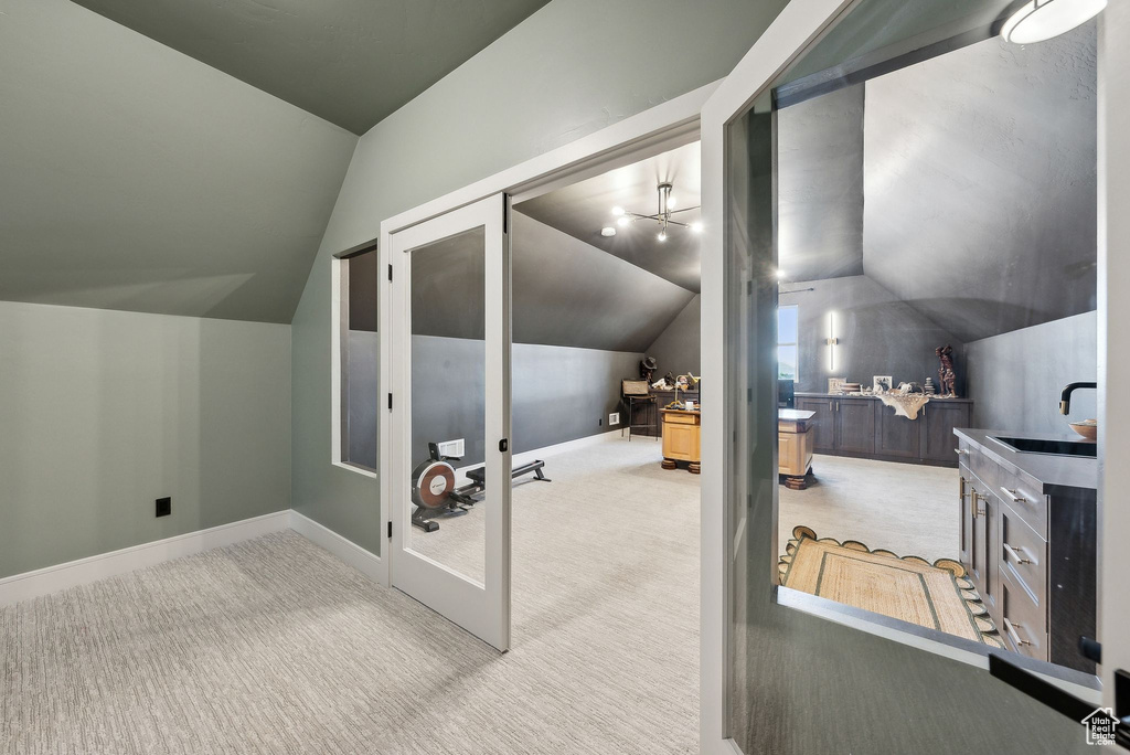 Bonus room with baseboards, vaulted ceiling, and light carpet