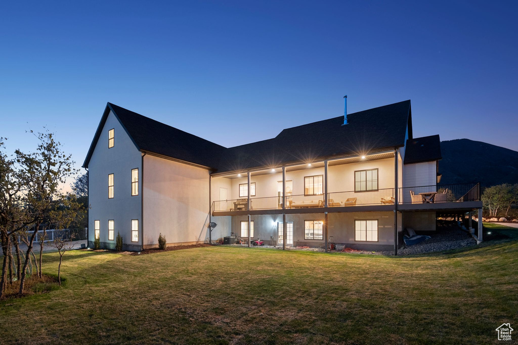 Rear view of property with a lawn and a balcony