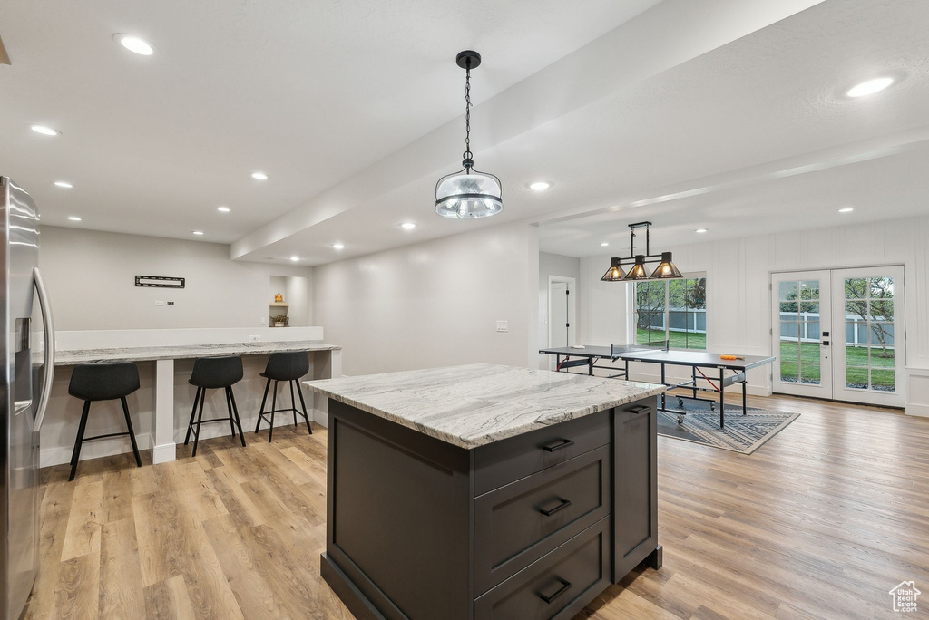 Kitchen with a center island, stainless steel refrigerator with ice dispenser, recessed lighting, light wood-type flooring, and decorative light fixtures
