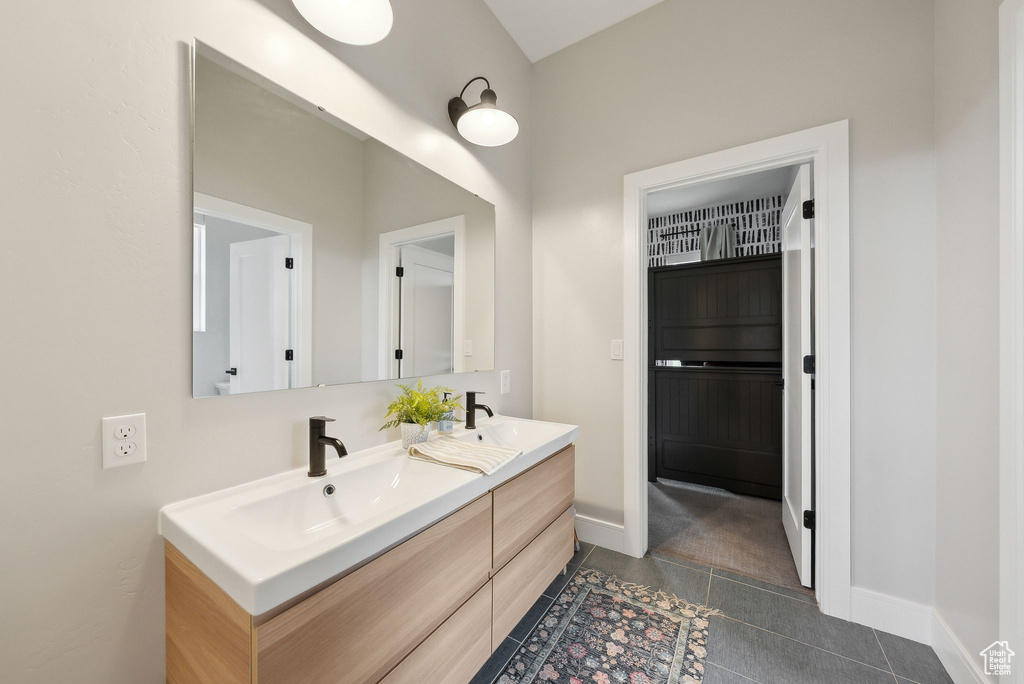 Full bath with a sink, baseboards, tile patterned flooring, and double vanity