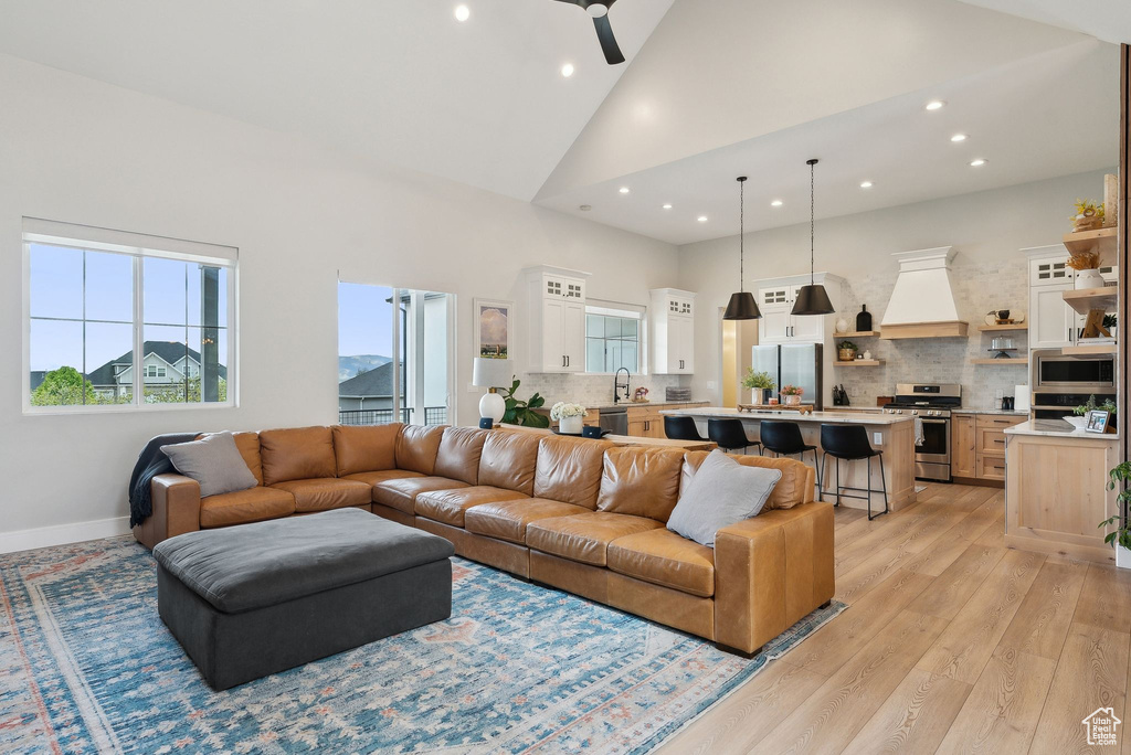 Living room featuring recessed lighting, high vaulted ceiling, ceiling fan, and light wood-style flooring