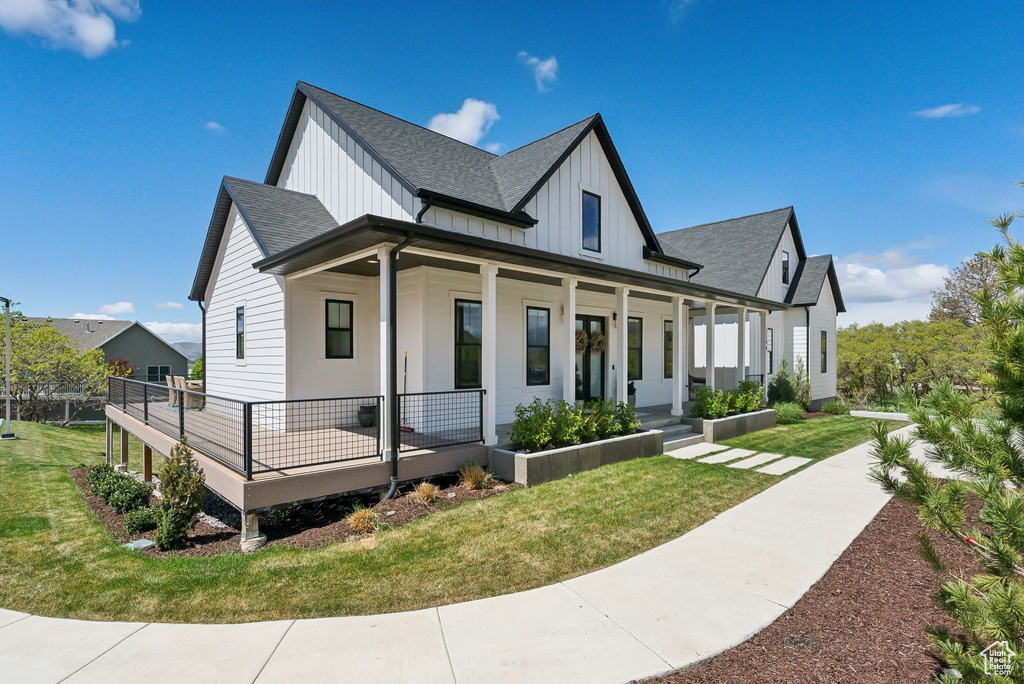 View of front of home with a shingled roof, board and batten siding, a porch, and a front yard