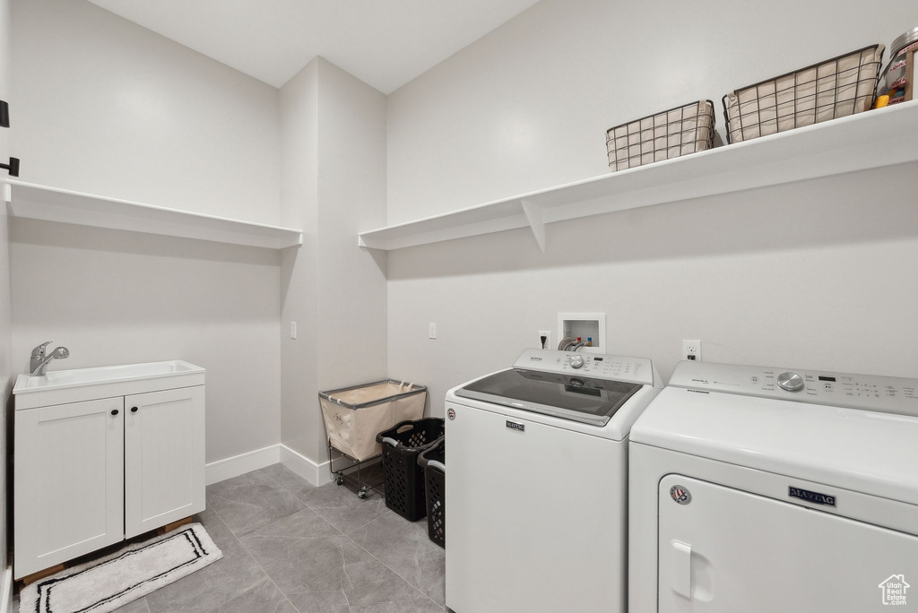 Laundry area featuring a sink, baseboards, washing machine and dryer, and cabinet space