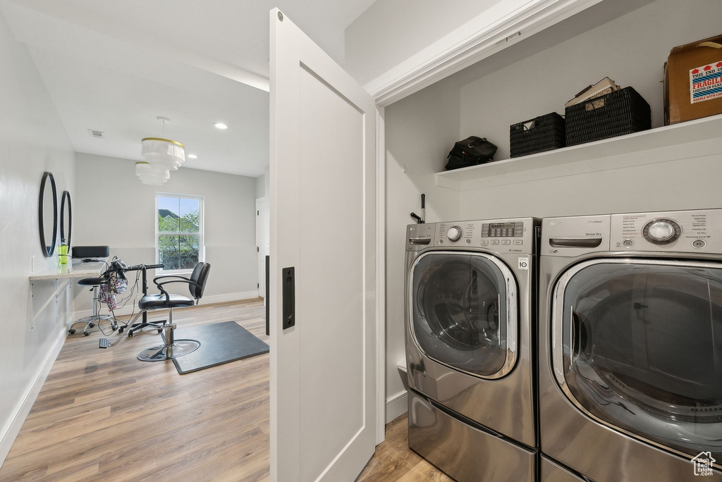 Washroom with baseboards, laundry area, washing machine and dryer, and wood finished floors