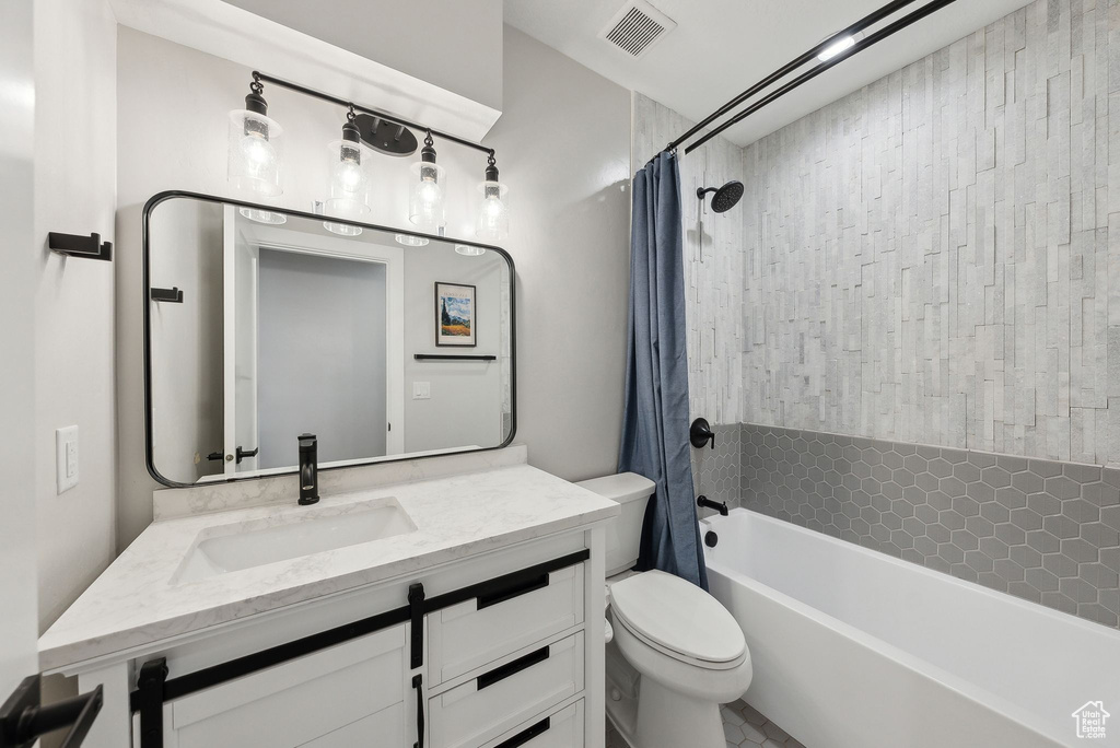 Bathroom with shower / bath combo with shower curtain, toilet, visible vents, and vanity